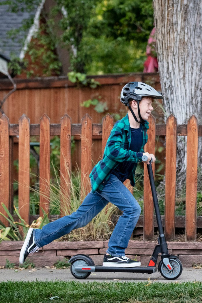 Child riding a kids' e-scooter with foot-push start, enjoying active outdoor play